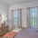 bedrrom with large bed an dresser with 2 tall windows
