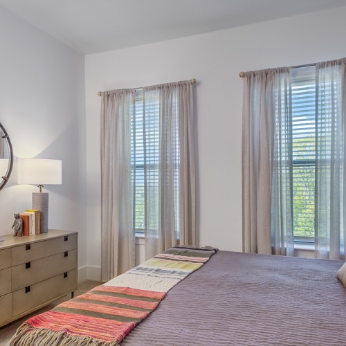 Settle into comfort at Enclave Piney Mountain bedrrom with large bed an dresser with 2 tall windows