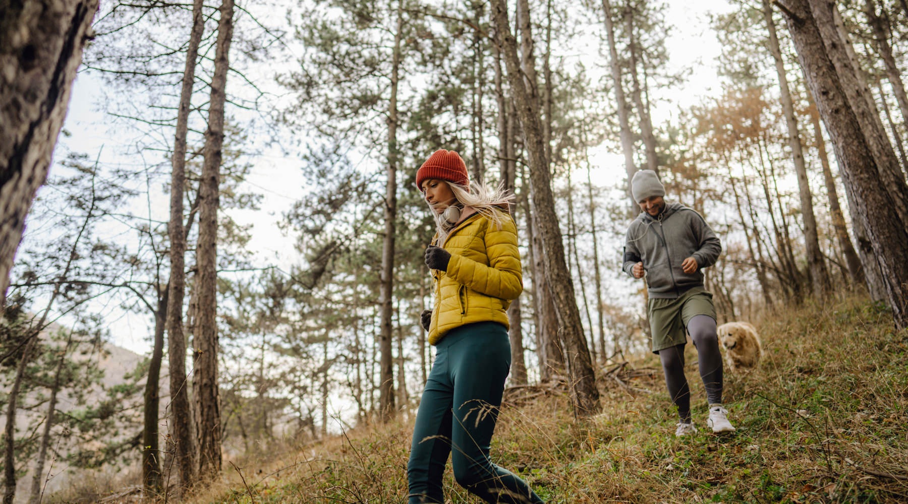 Man and woman walking through wooded trail.